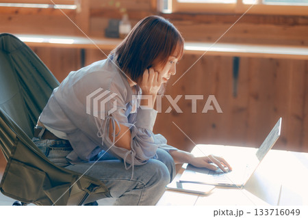 椅子にゆったり座って作業する20代女性のワークシーン 133716049
