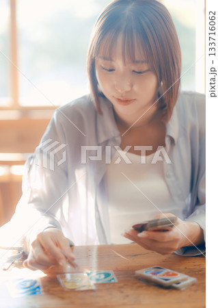 光の差すカフェでカードゲームを楽しむ20代女性 光の差すカフェでカードゲームを楽しむ20代女性 133716062