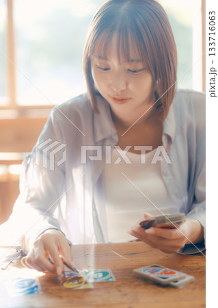 光の差すカフェでカードゲームを楽しむ20代女性 光の差すカフェでカードゲームを楽しむ20代女性 133716063