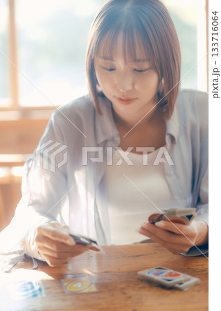 光の差すカフェでカードゲームを楽しむ20代女性 光の差すカフェでカードゲームを楽しむ20代女性 133716064
