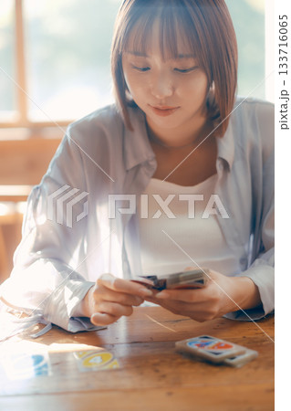 光の差すカフェでカードゲームを楽しむ20代女性 光の差すカフェでカードゲームを楽しむ20代女性 133716065
