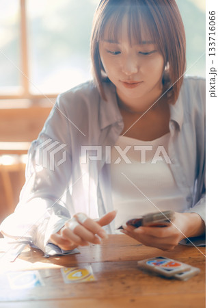 光の差すカフェでカードゲームを楽しむ20代女性 光の差すカフェでカードゲームを楽しむ20代女性 133716066
