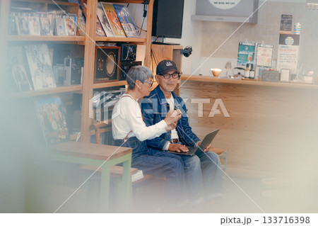 シニア夫婦がカフェでパソコンとスマホを使って調べものをするシーン シニア夫婦がカフェでパソコンとスマホを使って調べものをするシーン 133716398