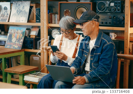シニア夫婦がカフェでパソコンとスマホを使って調べものをするシーン シニア夫婦がカフェでパソコンとスマホを使って調べものをするシーン 133716408