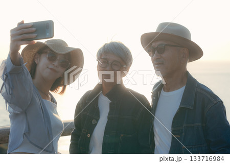 夕暮れの海辺で親子3人が自撮りを楽しむシーン 夕暮れの海辺で親子3人が自撮りを楽しむシーン 133716984