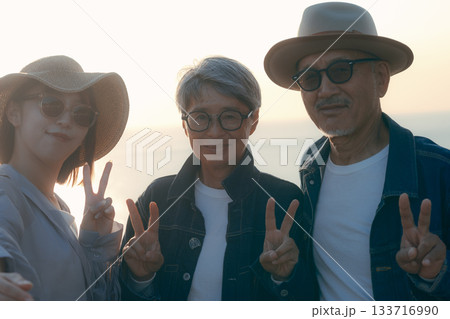 夕暮れの海辺で親子3人が自撮りを楽しむシーン 夕暮れの海辺で親子3人が自撮りを楽しむシーン 133716990