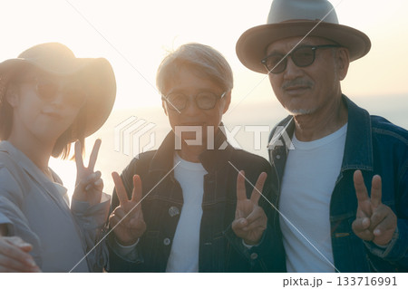 夕暮れの海辺で親子3人が自撮りを楽しむシーン 夕暮れの海辺で親子3人が自撮りを楽しむシーン 133716991