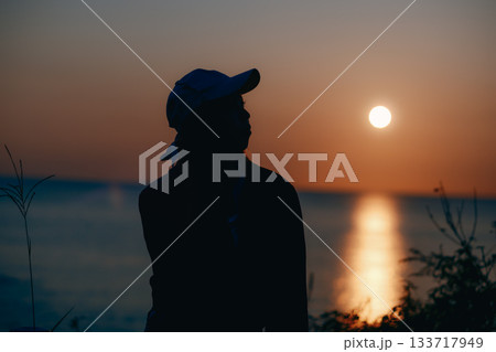 夕景に佇む若い女性のシルエット 133717949