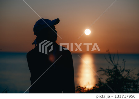 夕景に佇む若い女性のシルエット 133717950