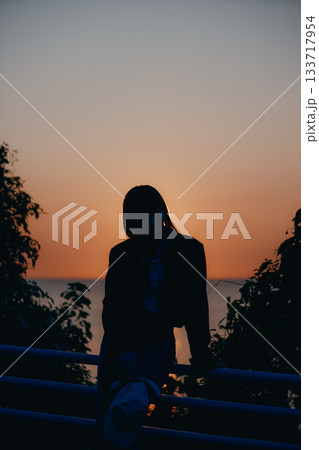 夕景に佇む若い女性のシルエット 133717954