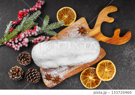 Traditional Christmas Stollen, sweet fruit loaf with sugar icing on wooden board and festive decor Traditional Christmas Stollen, sweet fruit loaf with sugar icing on wooden board and festive decor 133720460