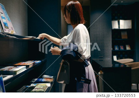 ホテルロビーでパンフレットを見る20代女性 ホテルロビーでパンフレットを見る20代女性 133720553