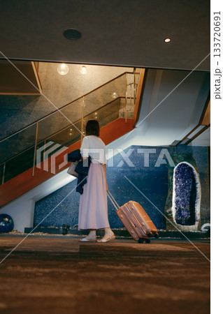 ホテルロビーに佇む20代女性とスーツケース 133720691