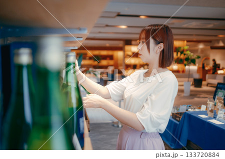 ホテルのお土産コーナーで地酒を選ぶ20代女性OL 133720884