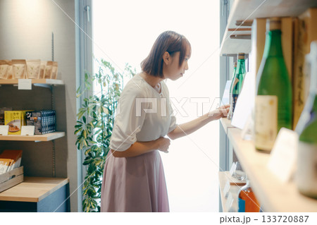 ホテルのお土産コーナーで地酒を選ぶ20代女性OL 133720887
