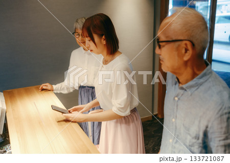 親子三人がホテルでチェックインするシーン 133721087