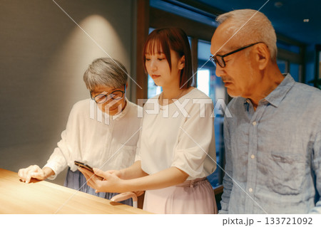 親子三人がホテルでチェックインするシーン 133721092