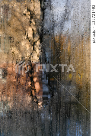vertical photo wet glass. foggy window showing faint autumn trees. condensation creates an abstract, dream-like effect, blurring colorful foliage outside. abstract glass background with water droplets vertical photo wet glass. foggy window showing faint autumn trees. condensation creates an abstract, dream-like effect, blurring colorful foliage outside. abstract glass background with water droplets 133721492