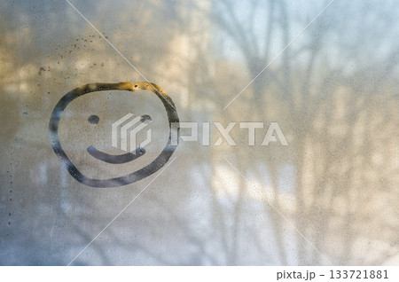Single happy face drawn on fogged glass radiates pure joy through water droplets. Temporary smiley grins through office glass. cheerful smile is concept of good mood. 133721881