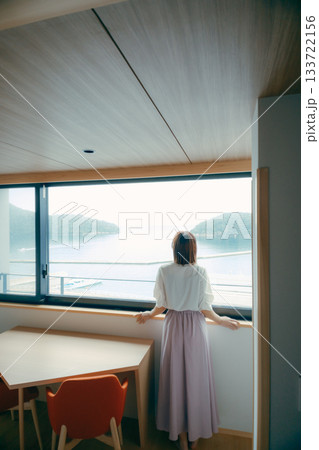 20代 女性がホテルの窓辺で景色を眺めるシーン 133722156