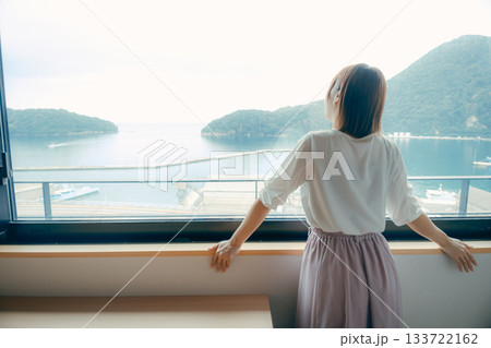 20代 女性がホテルの窓辺で景色を眺めるシーン 133722162