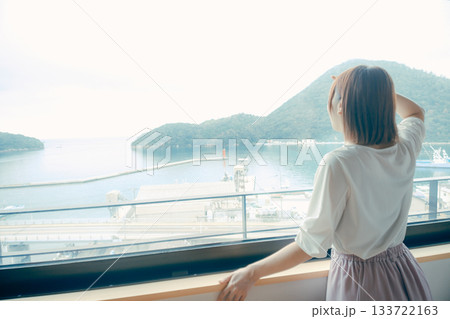 20代 女性がホテルの窓辺で景色を眺めるシーン 133722163