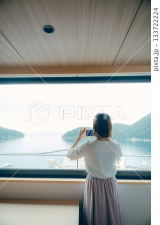 20代 女性がホテルの窓辺でスマホ撮影するシーン 133722224