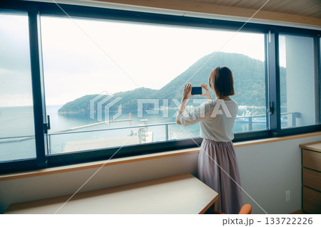 20代 女性がホテルの窓辺でスマホ撮影するシーン 20代 女性がホテルの窓辺でスマホ撮影するシーン 133722226