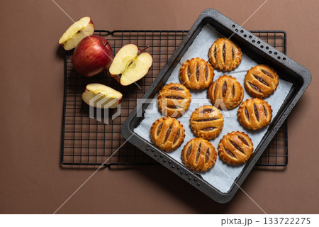 Freshly Baked Apple Pastries on a Wire Rack with Whole Apples 133722275