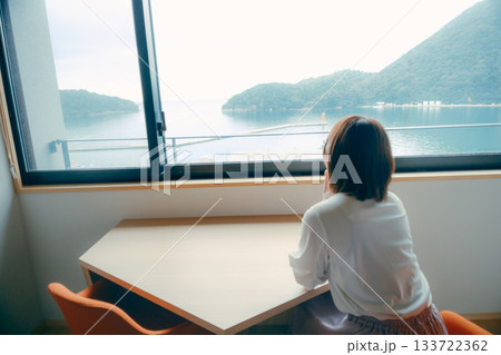 20代 女性がホテル客室で海と山の景色を眺めるシーン 133722362