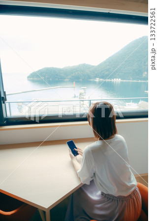 20代 女性がホテル客室でスマホを見るシーン 20代 女性がホテル客室でスマホを見るシーン 133722561