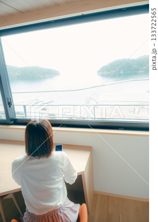 20代 女性がホテル客室でスマホを見るシーン 133722565