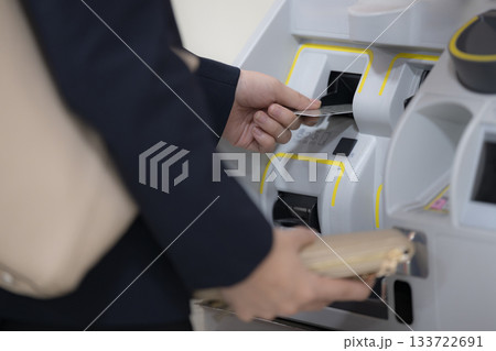 券売機・自動チェックイン機を操作、チャージなどをするスーツの女性　顔無し 133722691