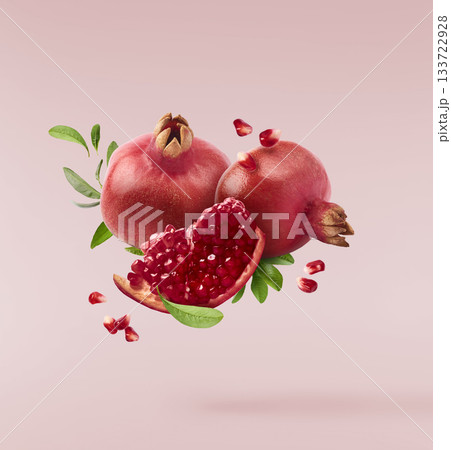 Flying in air fresh ripe whole and cut pomegranate with seeds and leaves isolated. High resolution image Flying in air fresh ripe whole and cut pomegranate with seeds and leaves isolated. High resolution image 133722928