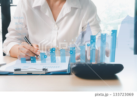 Businesswoman analyzing financial reports with digital bar charts and data graphs, representing financial analysis, business growth, investment planning, budget management, strategic decision-making. Businesswoman analyzing financial reports with digital bar charts and data graphs, representing financial analysis, business growth, investment planning, budget management, strategic decision-making. 133723069