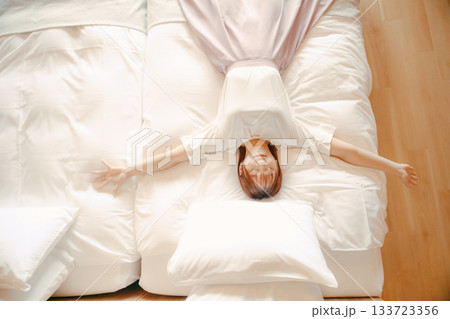 20代 女性がホテルの白いベッドでリラックスするシーン 20代 女性がホテルの白いベッドでリラックスするシーン 133723356