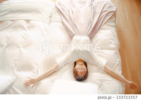 20代 女性がホテルの白いベッドでリラックスするシーン 20代 女性がホテルの白いベッドでリラックスするシーン 133723357