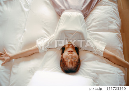 20代 女性がホテルの白いベッドでリラックスするシーン 20代 女性がホテルの白いベッドでリラックスするシーン 133723360