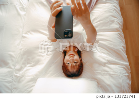 20代 女性がホテルのベッドでスマホを持ち自撮りするシーン 20代 女性がホテルのベッドでスマホを持ち自撮りするシーン 133723741