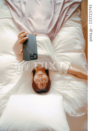 20代 女性がホテルのベッドでスマホを持ち自撮りするシーン 20代 女性がホテルのベッドでスマホを持ち自撮りするシーン 133723743