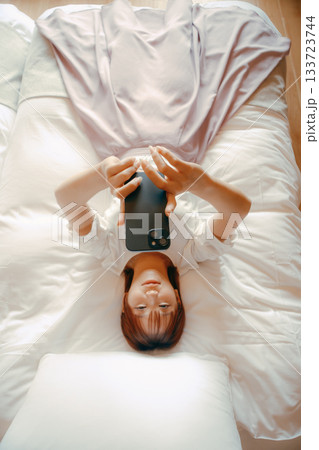 20代 女性がホテルのベッドでスマホを持ち自撮りするシーン 20代 女性がホテルのベッドでスマホを持ち自撮りするシーン 133723744