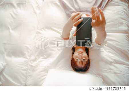20代 女性がホテルのベッドでスマホを持ち自撮りするシーン 20代 女性がホテルのベッドでスマホを持ち自撮りするシーン 133723745