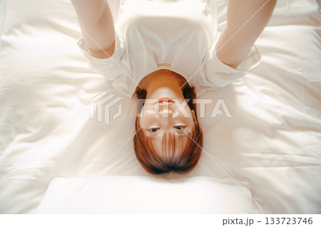 20代 女性がホテルのベッドでスマホを持ち自撮りするシーン 133723746