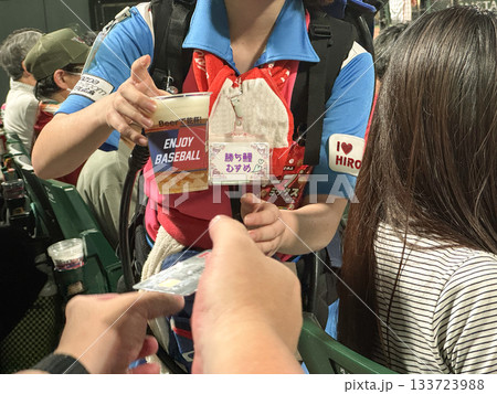マツダスタジアム広島の観戦スタンドで生ビールを渡す売り子さんとクレジットカードを差し出すお客さん 133723988