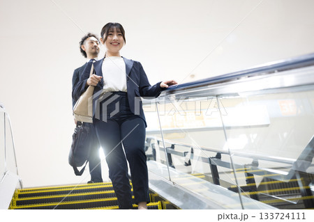 空港や駅のエスカレーターを降りるスーツ姿のキャリア女性のビジネス移動シーン 空港や駅のエスカレーターを降りるスーツ姿のキャリア女性のビジネス移動シーン 133724111