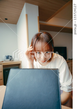 20代 女性がホテルの部屋で鏡を見て身だしなみを整えるシーン｜旅行・宿泊・メイク 133724127