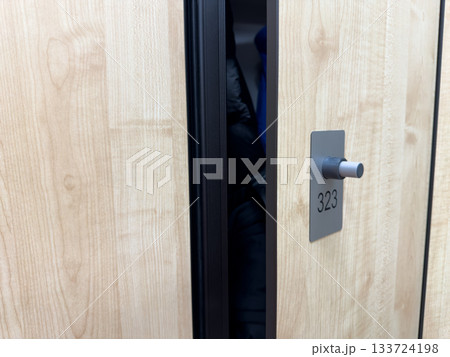 Open gym locker door with personal belongings. Wooden door features modern closing mechanism and personal locker number. Concept for storing belongings while working out at gym Open gym locker door with personal belongings. Wooden door features modern closing mechanism and personal locker number. Concept for storing belongings while working out at gym 133724198