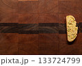 Single, homemade, orange and pistachio holiday biscotti on a wooden cutting board 133724799
