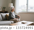 明るい部屋のソファで窓の外を見る白髪の高齢女性 133724991