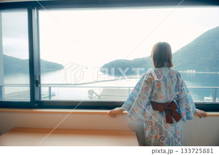 浴衣姿の20代女性がホテルの窓から景色を眺めるシーン 133725881